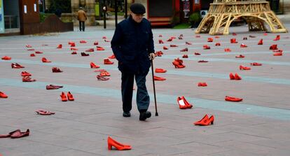 Un hombre camina por la plaza de Mariano Granados llena de zapatos en recuerdo a las víctimas de violencia machista.