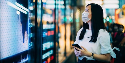 Una inversora consulta la evolución de las Bolsas en una pantalla en el distrito financiero de Hong Kong.