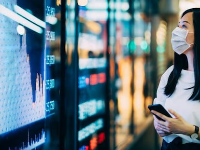 Una inversora consulta la evolución de las Bolsas en una pantalla en el distrito financiero de Hong Kong.