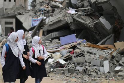 Tres estudiantes palestinas observan los restos de un edificio destruido durante los ataques aéreos israelíes, próximo a una escuela que también se vio damnificada, en Gaza. 