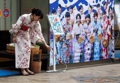 Una mujer vistiendo el 'yukata' (kimono de verano) esparce agua sobre el asfalto según el ritual tradicional japonés llamado 'uchimizu', que, entre otros propósitos, refresca el aire al evaporarse el agua, el 23 de julio de 2018 en Tokio.