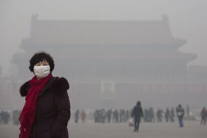 Una mujer china lleva una máscara mientras camina a través de una muy vaga la Plaza de Tiananmen.