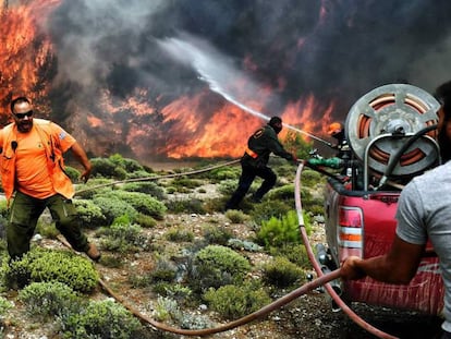 Bomberos y voluntarios intentan extinguir las llamas de un incendio próximo a la ciudad de Kineta, cerca de Atenas.