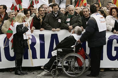 El líder del PP, Mariano Rajoy, habla con una víctima del terrorismo durante la marcha, en la que se situó tras la segunda pancarta.