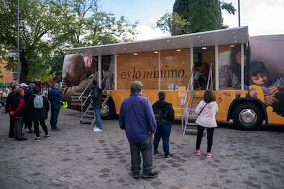 Gente hace cola para entrar en un autobús que informa sobre el Ingreso Mínimo Vital en Parla en octubre de 2022.