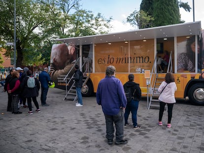 Gente hace cola para entrar en un autobús que informa sobre el Ingreso Mínimo Vital en Parla en octubre de 2022.