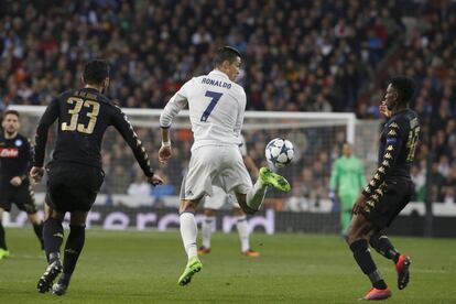 El delantero portugués del Real Madrid, Cristiano Ronaldo (c), golpea de espuela el balón ante los jugadores del Nápoles, el defensa español Raúl Albiol (i) y el centrocampista guineano, Amadou Diawara.