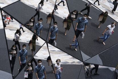Los peatones se reflejan en un espejo colocado en el techo de un centro comercial de Tokio (Japón).