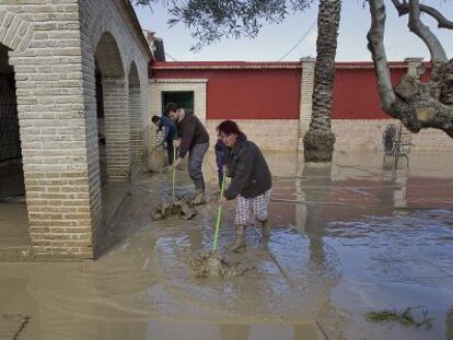 Una familia limpia su vivienda tras una inundación en Écija.