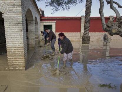 Una familia limpia su vivienda tras una inundaci&oacute;n en &Eacute;cija.