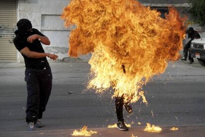 Las llamas devoran a un manifestante en Sanabis, en Bahr&eacute;in, despu&eacute;s de que le explote en la mano un c&oacute;ctel molotov por un disparo de la polic&iacute;a.