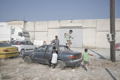 Algunos niños juegan entre los restos de coches frente a la clínica de MSF en Moria.