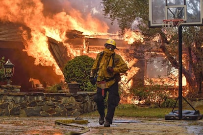 Un bombero trabaja este lunes en la extinción del incendio mientras las llamas devoran una casa en Anaheim Hills (California).