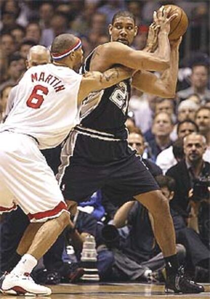 Tim Duncan, de los Spurs, evita el ataque de Kenyon Martin, de los Nets.