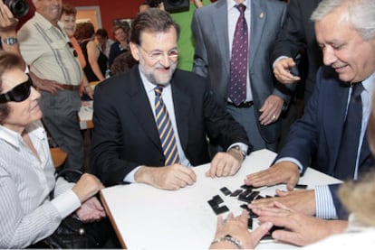 Rajoy y Arenas juegan al dominó durante su visita a un centro vecinal de Almería.