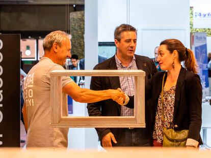 Un comercial saluda a dos visitantes en una feria de construcción en Barcelona.