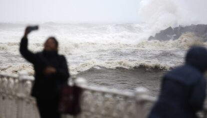 Una mujer se fotografía mientras las olas entras en el río Urumea de San Sebastián (Gipuzkoa) durante el temporal.