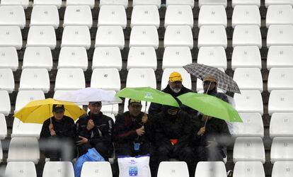 Un pequeño grupo de espectadores se protege de la lluvia en las gradas del circuito de Jerez.