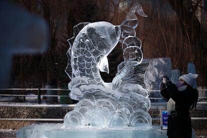 Una de las esculturas de hielo en el parque Zhaolin, uno de los escenarios del Festival de Hielo y Nieve de Harbin. En la imagen, una mujer fotografía el pez de hielo el 5 de enero de 2025.  