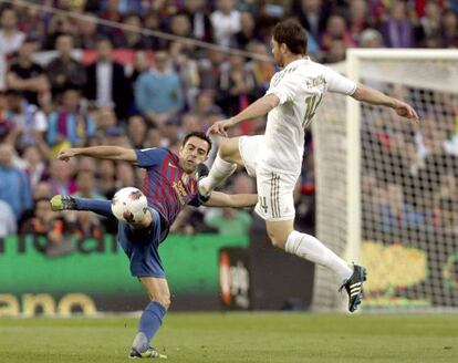 Xavi pelea un balón con Xabi Alonso.