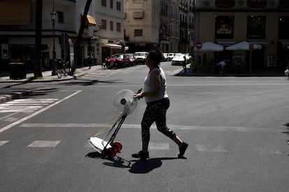Una mujer transporta un ventilador en una carretilla este jueves en Sevilla.