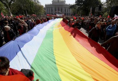 Uma grande bandeira LGBT é carregada por manifestantes durante a celebração do dia 1º de maio em Viena (Áustria).