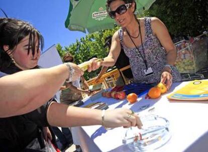 Una mujer apaga un cigarrillo antes de recibir una pieza de fruta en Alcobendas.