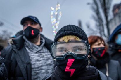 Una joven, con gafas y una máscara con un rayo rojo, participa en una protesta en favor del movimiento por los derechos de las mujeres, en Varsovia (Polonia).