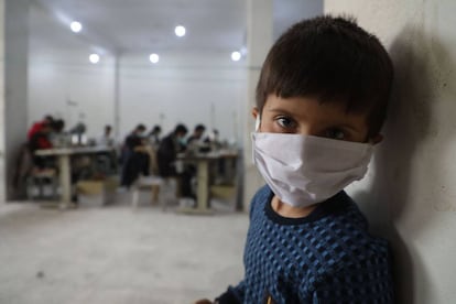 Un niño observa cómo un grupo de voluntarios hacen máscaras faciales protectoras en un taller en la ciudad de Idlib, en el noreste de Siria.  