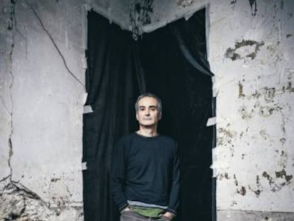 Olivier Assayas posa apoyado en una pared que es como nuestra enferma sociedad: algo roto con un fondo muy negro.