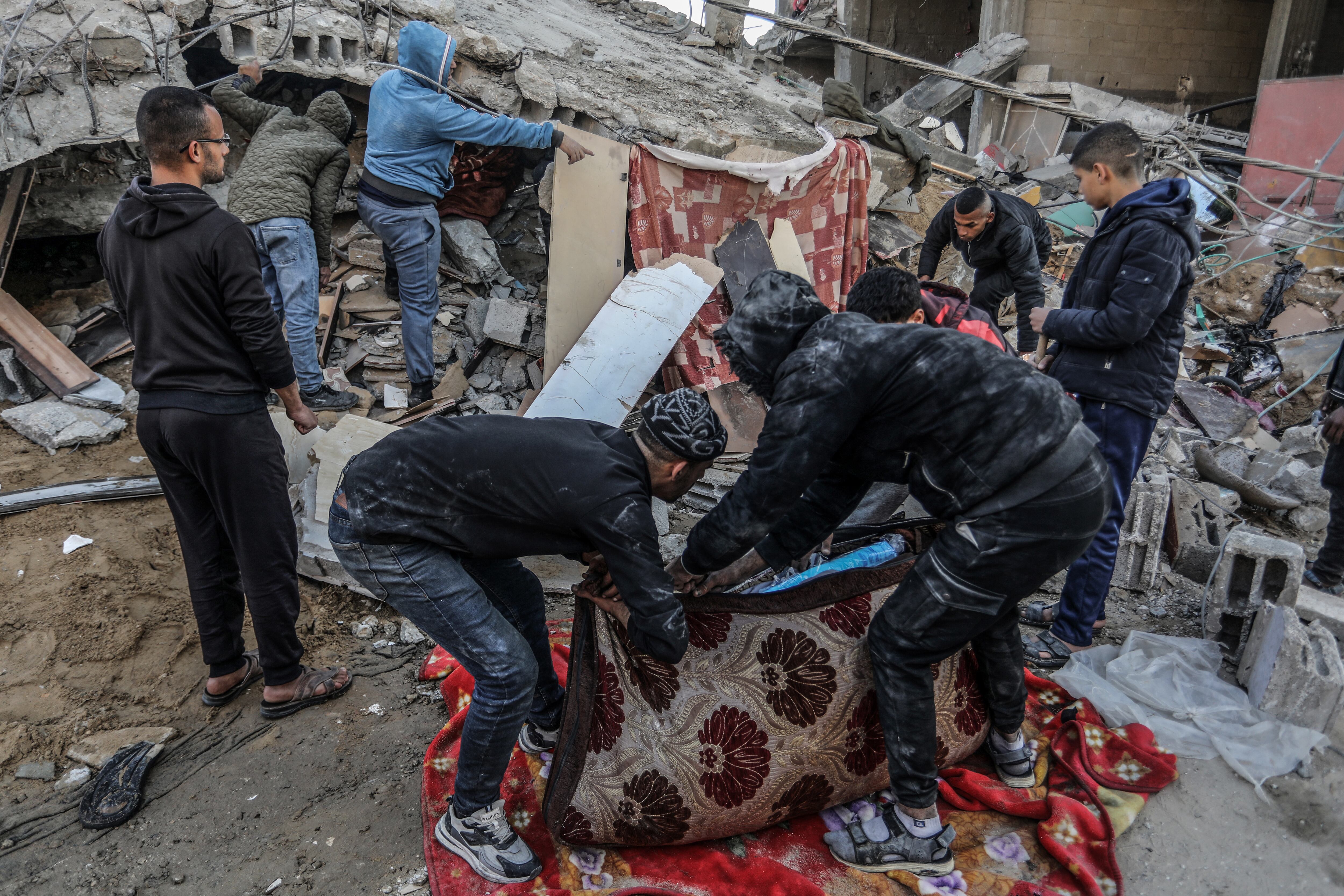 Varias personas buscan supervivientes entre los escombros de  un edificio colapsado tras los ataques israelíes sobre Rafah, este lunes. 