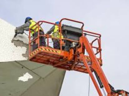 Dos operarios trabajan, desde una plataforma elevadora, en la retirada del revestimiento de la cubierta del Palau de les Arts tras los deprendimientos del pasado mes de diciembre.