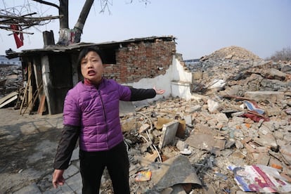 Cao Mingyun, hija de Cao Wenxia, de 75 años y dueña de una 'casa clavo', habla con un periodista frente a su vivienda en Hefei, provincia de Anhui, el 29 de enero de 2010. La familia de Cao se negaba a mudarse debido a no estar satisfechos con la compensación ofrecida por su casa, que estaba a punto de ser demolida para dar paso a un nuevo proyecto comercial.