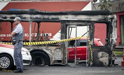 Um policial em frente a um &ocirc;nibus queimado na zona sul de S&atilde;o Paulo.