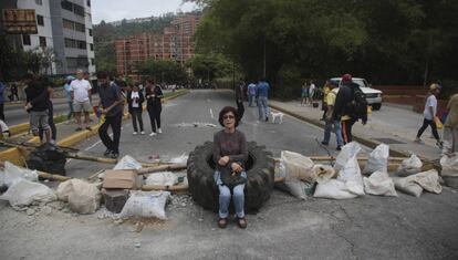 Una mujer sentada sobre un neumático en Caracas, Venezuela. Los residentes han bloqueado calles con bolsas de basura para protestar contra la idea de reescribir la nueva Constitución y la situación política en el país.