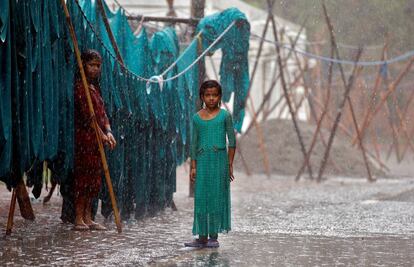 Unas muchachas indias se dejan fotografiar bajo la lluvia del monzón junto a su colada, en Nueva Delhi.