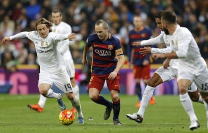 Iniesta conduce entre rivales del Madrid.