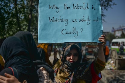 Una afgana sostiene un cartel en el que se lee "¿Por qué el mundo nos está mirando en silencio y cruelmente?"
