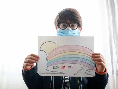 Un niño con mascarilla enseña un dibujo que ha hecho de un arcoiris y la frase 'Todo irá bien'.