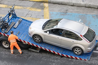 Trabajador de asistencia en carretera levantando un coche con una grúa en Galicia.