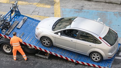 Trabajador de asistencia en carretera levantando un coche con una grúa en Galicia.