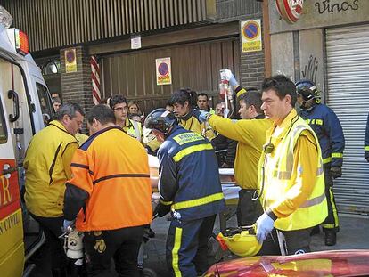 Sanitarios del Samur y bomberos trasladan al herido al interior de una ambulancia.