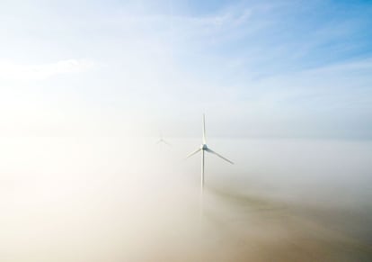 Molinos de viento entre la niebla, en un campo cerca de Hanover (Alemania).