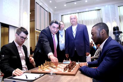 El presidente adjunto de la FIDE, Georgios Makrópulos, realiza el saque de honor de la 1ª ronda, en el tablero de Magnus Carlsen contra el nigeriano Balogun. Junto a él, Alon Shulman (árbitro) y, más a la derecha, Zurab Azmaiparashvili