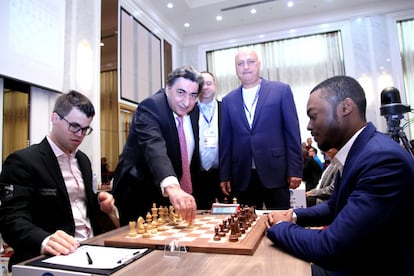 El presidente adjunto de la FIDE, Georgios Makrópulos, realiza el saque de honor de la 1ª ronda, en el tablero de Magnus Carlsen contra el nigeriano Balogun. Junto a él, Alon Shulman (árbitro) y, más a la derecha, Zurab Azmaiparashvili