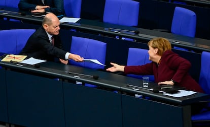 El ministro de Finanzas alemán, el socialdemócrata Olaf Scholz, entrega un documento a la canciller alemana, la conservadora Angela Merkel, en una sesión en el Bundestag, el pasado jueves en Berlín.