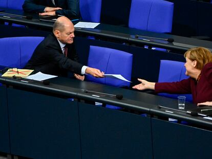 El ministro de Finanzas alemán, el socialdemócrata Olaf Scholz, entrega un documento a la canciller alemana, la conservadora Angela Merkel, en una sesión en el Bundestag, el pasado jueves en Berlín.