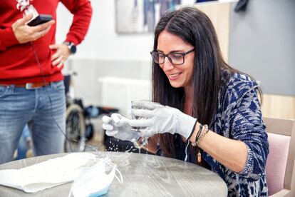 Patricia González trata de beber agua con unos guantes que le provocan temblores, en un curso de empatía en una residencia de la empresa Vitalia en Madrid.