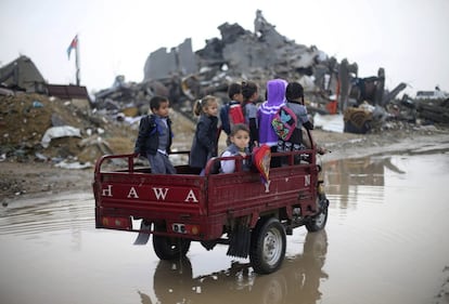 Escolares palestinos recorren bajo la lluvia las calles de Khan Younis, en el sur de la franja de Gaza.