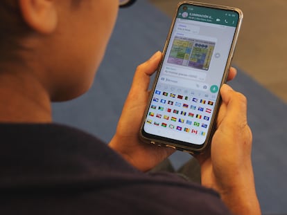 Una mujer mira los emojis de las banderas de Whatsapp.